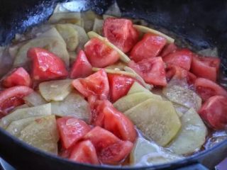 青椒土豆片,接着放入番茄块，小火炒至番茄软烂、出现汤汁。