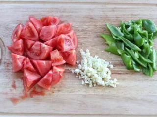 青椒土豆片,将番茄的外皮剥掉切成滚刀块，青椒切斜块，大蒜剁成蒜末备用。