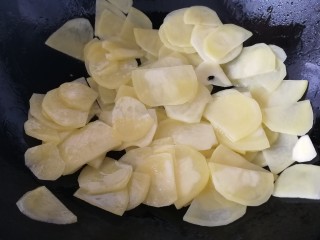 青椒土豆片,油温6成热放入土豆片，文火翻炒均匀。