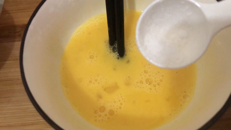 耳光炒饭,碗里打入两个鸡蛋搅散、放入适量的盐搅匀一下