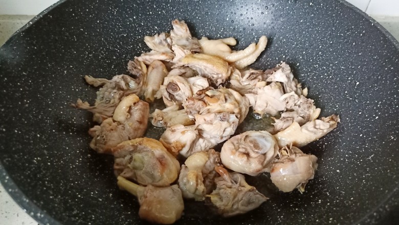 新疆大盘鸡,翻炒到鸡块表面微黄，炒出鸡肉当中的油脂，放适量姜蒜翻炒。