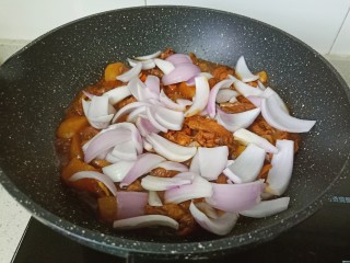 新疆大盘鸡,炖煮到汤汁差不多时加入洋葱翻炒至断生，加盐调味。
