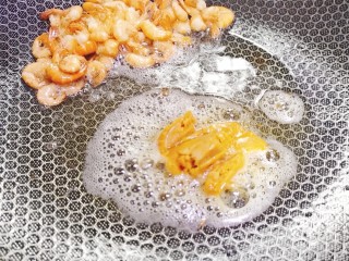 耳光炒饭,然后将河虾推至锅边，将鸭蛋黄炒香