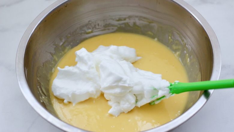 KITTY异形戚风蛋糕,先取三分之一蛋白糊，加入到蛋黄糊里翻拌均匀。