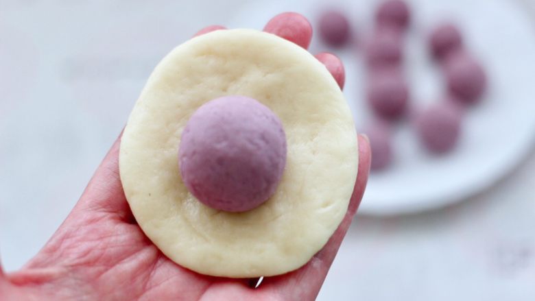 奶香紫薯芋泥华夫饼,松弛好的小面团，用手摁扁，放入馅料。