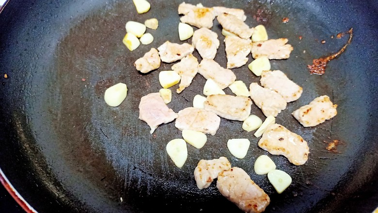 干锅西兰花,锅中放入少量油，油热后放入猪肉，炒至猪肉变色放入蒜瓣 