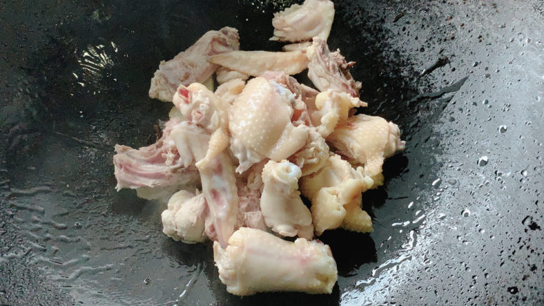 新疆大盘鸡,加入焯过水的三黄鸡块，转中火煸炒，让鸡皮在油锅中炒出香味。