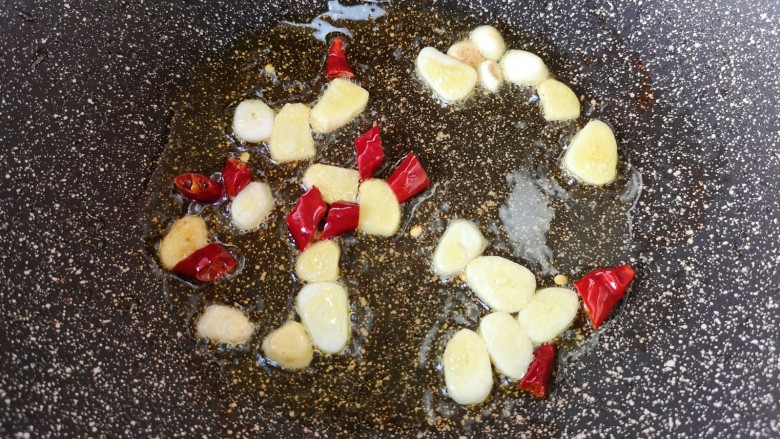 干锅西兰花,锅底留余油，下入蒜片、姜片和干红辣椒炒香。