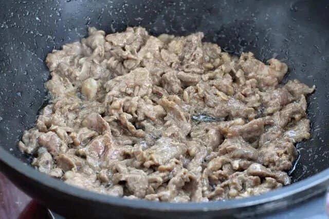 小炒牛肉,锅中倒适量食用油烧至五成热，下入腌制好的牛肉炒至变色盛出。