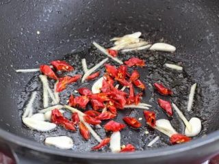 小炒牛肉,就着锅中底油放入姜丝、蒜片和红干椒，小火炒出香味。
