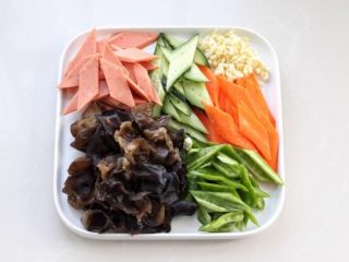 红烧日本豆腐,准备其他辅料：黑木耳提前泡发，洗净撕成小片。火腿肠、黄瓜、胡萝卜和辣椒切成斜片，大蒜切碎备用。