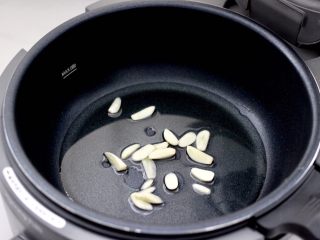 梅豆鸡肉小炒,炒菜机的锅中倒入适量油，放入大蒜片。