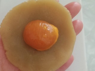 蛋黄莲蓉月饼,取一个白莲蓉，按扁，包入一颗熟蛋黄