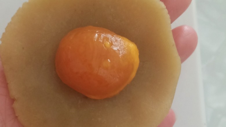 蛋黄莲蓉月饼,取一个白莲蓉，按扁，包入一颗熟蛋黄