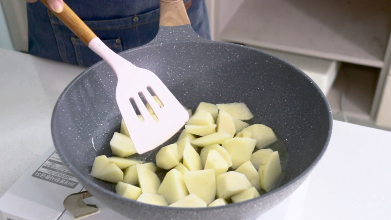 红烧土豆,将控干水分的土豆放入锅中煎炸至两面金黄