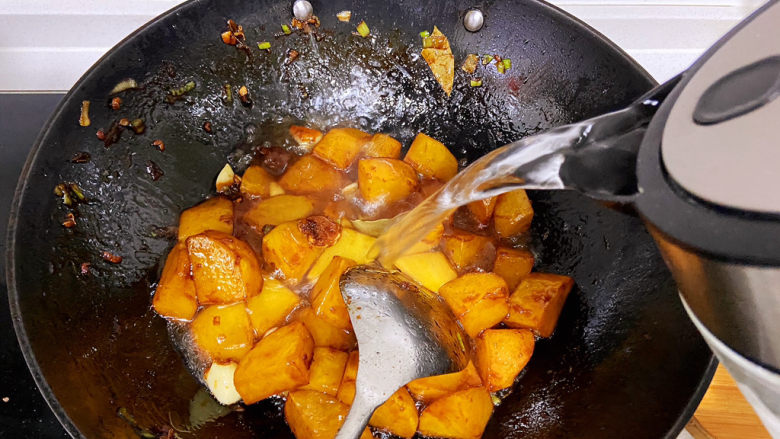 红烧土豆,翻炒至土豆上色变得金黄，添入适量的水，没过土豆即可。可以加入适量盐。