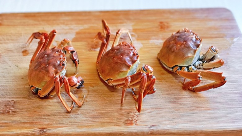 蒜泥螃蟹,取出煮好的蟹，放在砧板上，把下面的壳掰掉。