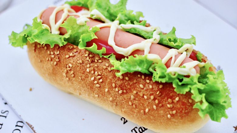 德式热狗面包,从面包中间切开，不要切到底，边上放入生菜和番茄片，中间放入火腿肠，上面挤上沙拉酱就可以享用了。