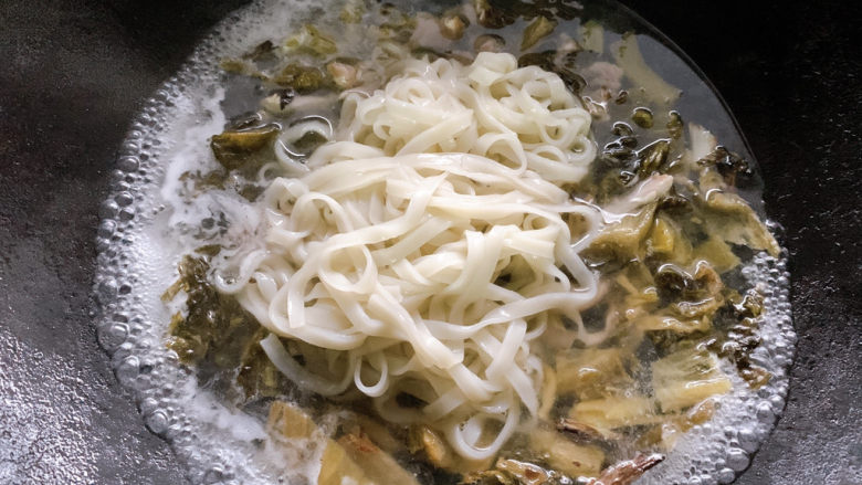 酸菜肉丝面,夹起后，加入一侧沸腾好的酸菜肉丝汤底中