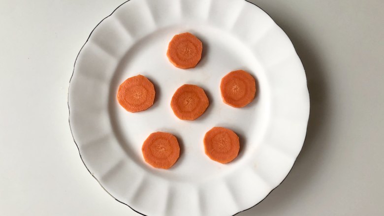 鲜虾蔬菜丸子,胡萝卜去皮，切成片，摆在盘子里，做丸子的底座。