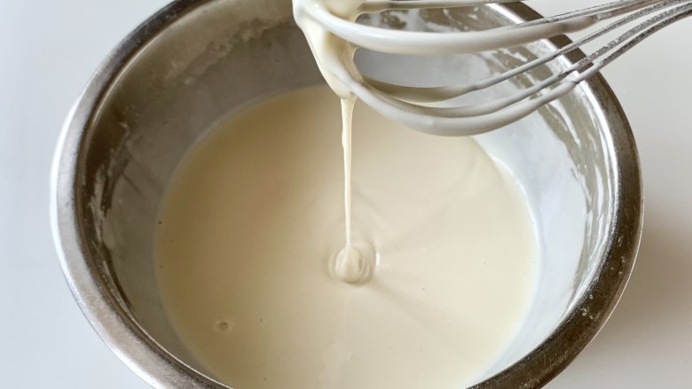 奶香鸡蛋糯米蒸糕,搅拌成均匀顺滑、没有结块的面糊，提起蛋抽，面糊可以自由滴落。这里不需要讲究手法，糯米粉没有筋度，不会像面粉一样起筋，可以随意搅拌。
