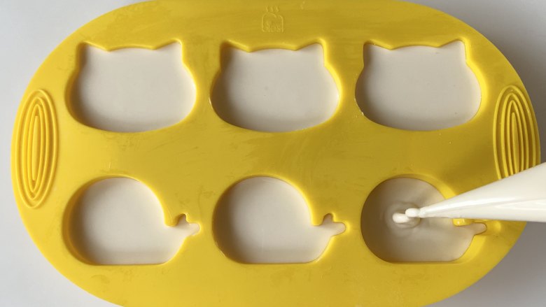奶香鸡蛋糯米蒸糕,在裱花袋底部剪一个口，把面糊挤入模具中。
