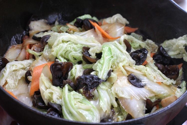 白菜炒肉片,再将白菜叶、木耳和胡萝卜一同放入锅中，翻炒约一分钟。