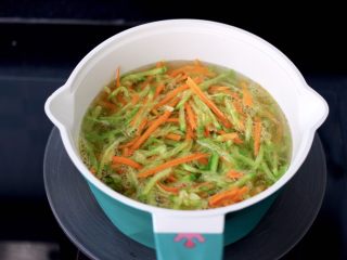 萝卜豆腐丸子,锅中倒入适量清水烧开，放入萝卜和胡萝卜丝开始焯水。
