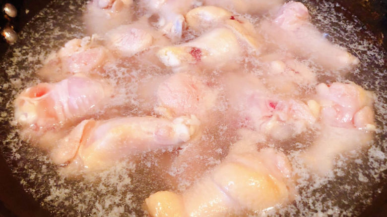 可乐鸡翅根,锅中烧开水放入鸡翅根同时倒入料酒焯水断生同时去除多余的油脂和杂质