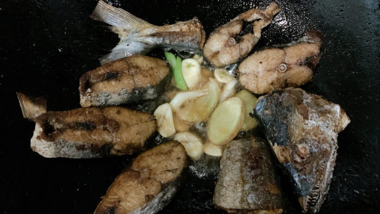 红烧鲅鱼,将锅中煎好的鱼肉移开留出一定空隙，加入姜蒜片、葱白爆香。