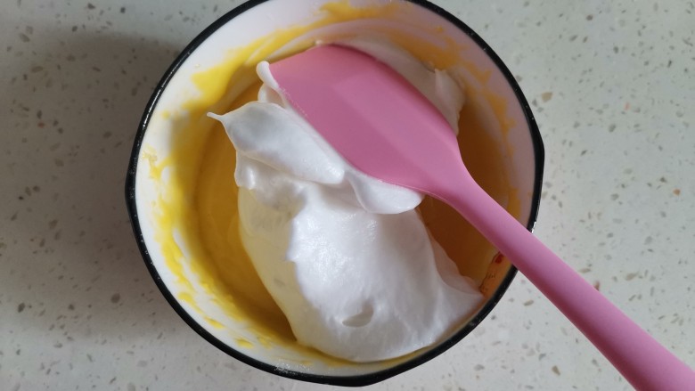 舒芙蕾蛋糕,取1/3蛋白霜到蛋黄糊里从下至上翻拌均匀，注意手法不能画圈搅拌，会消泡