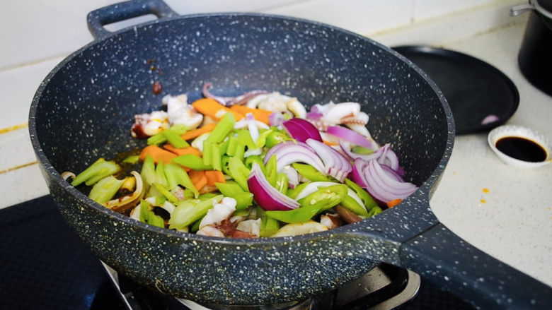西芹炒鱿鱼,倒入提前准备好的西芹、洋葱、杭椒、胡萝卜继续翻炒均匀。