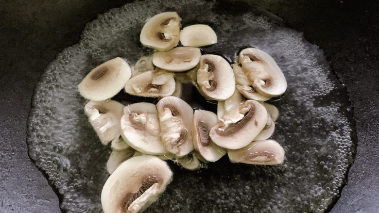 奶油蘑菇意面,口蘑切成片，入热水中汆烫。