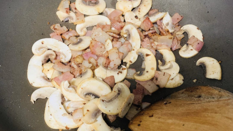 奶油蘑菇意面,锅中放黄油，黄油融化以后，将蘑菇、香肠和培根倒入锅中炒香。