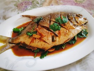 红烧金鲳鱼,盛盘洒上适量香菜，把汤汁浇在鱼身上即可。