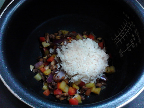 羊肉焖饭,将炒好的羊肉和蔬菜倒入电饭煲内胆中，加入大米，