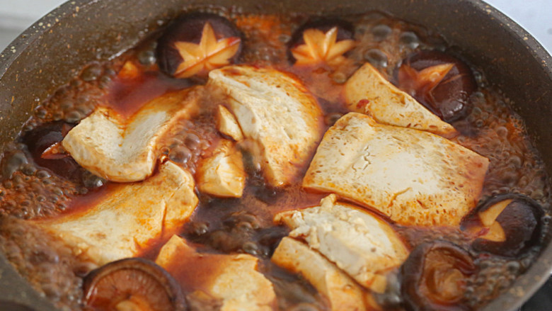 蘑菇炖豆腐,加入豆腐和蒜头加盖小火炖煮3分钟稍微翻一下，淋入淀粉水勾芡，起锅，放上葱丝即可上桌。