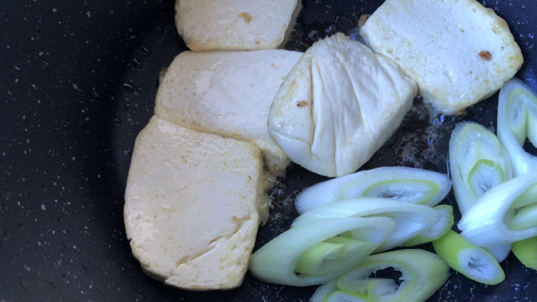 蘑菇炖豆腐,豆腐差不多煎好后，下入葱段略煎一下出香味即可。