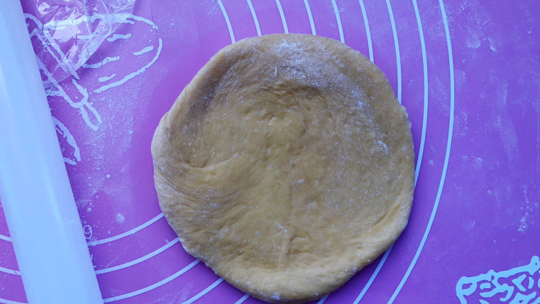 南瓜豆沙面包,取一个面团擀开成圆形。