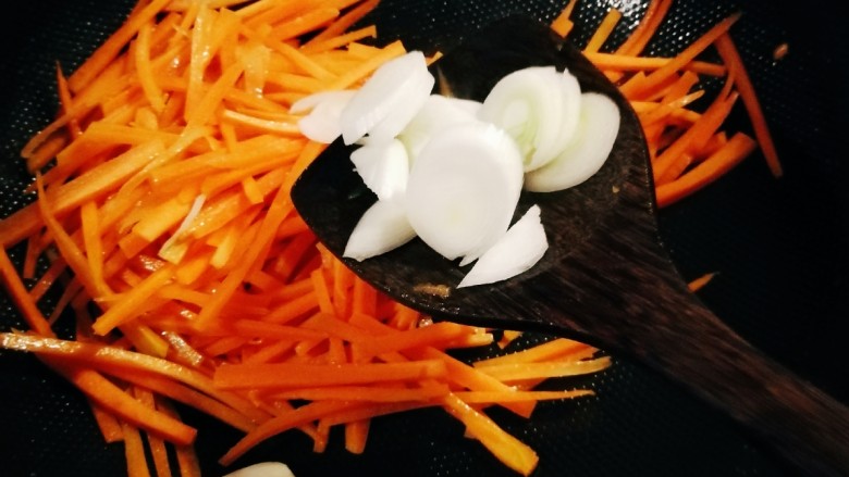 青椒炒胡萝卜,放入葱片增香，翻炒至胡萝卜丝变软。