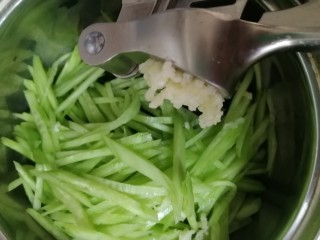 炝拌三丝,海带丝和黄瓜丝放入一个大碗里，2瓣蒜压成蒜蓉。