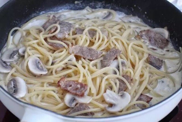 培根意大利面,将煮好的意面捞出来，放到煮至浓稠的汤汁锅中，用筷子混合拌匀。