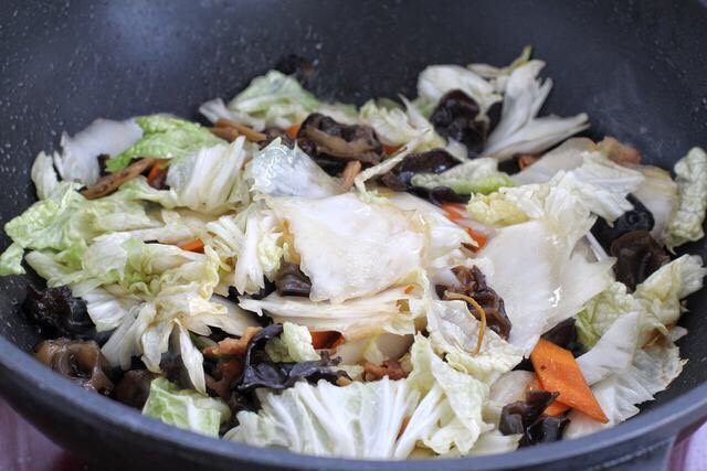 白菜炒木耳,把白菜片倒入锅中，继续用大火炒约两分钟至白菜变软。