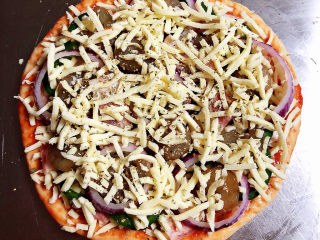 虾仁培根披萨,再摆上一层芝士碎，再撒上一层批萨草。将烤盘放入烤箱中，180度烤20度。