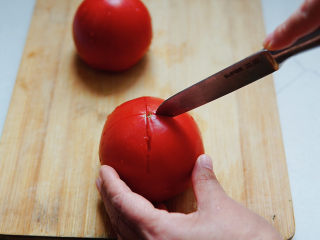 番茄豆腐汤,番茄冲洗干净外皮，在番茄的顶部，打十字花刀