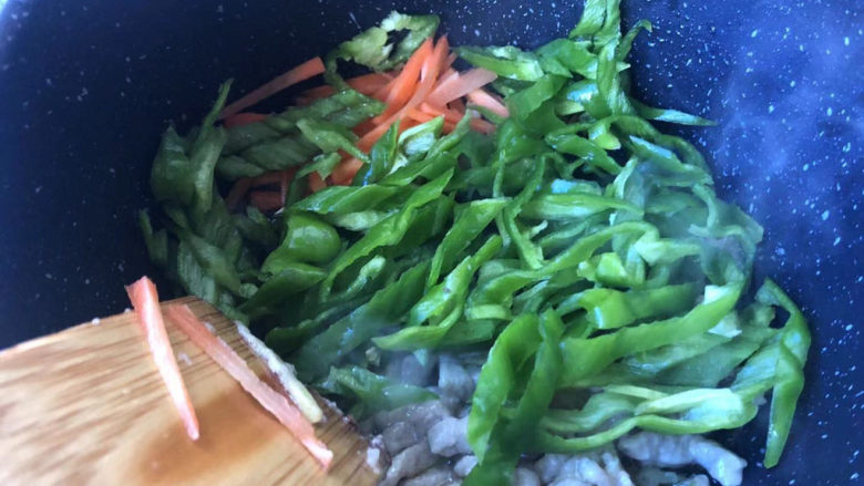 青椒肉丝面,接着放入青椒和胡萝卜，翻炒均匀断生。