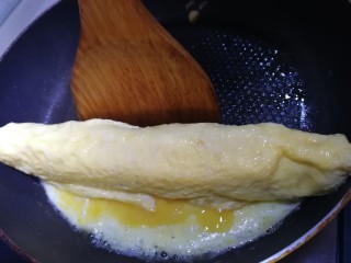 秋葵厚蛋烧,接着卷起蛋饼，卷起之后停10秒钟，让蛋液凝固定型。