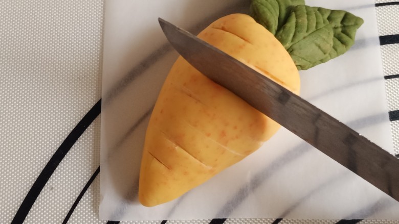 胡萝卜馒头,把胡萝卜放在烘焙纸上，用刀在萝卜上压出一条条的纹路