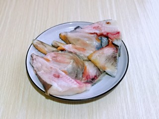 清蒸鸦片鱼,鱼头从中间剪开，一剪二，肉朝上放入盘中。