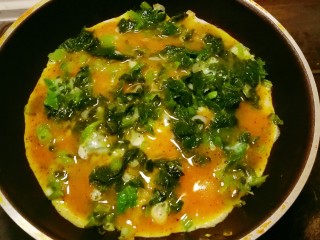 芹菜叶炒鸡蛋,随着加热鸡蛋液开始凝固。